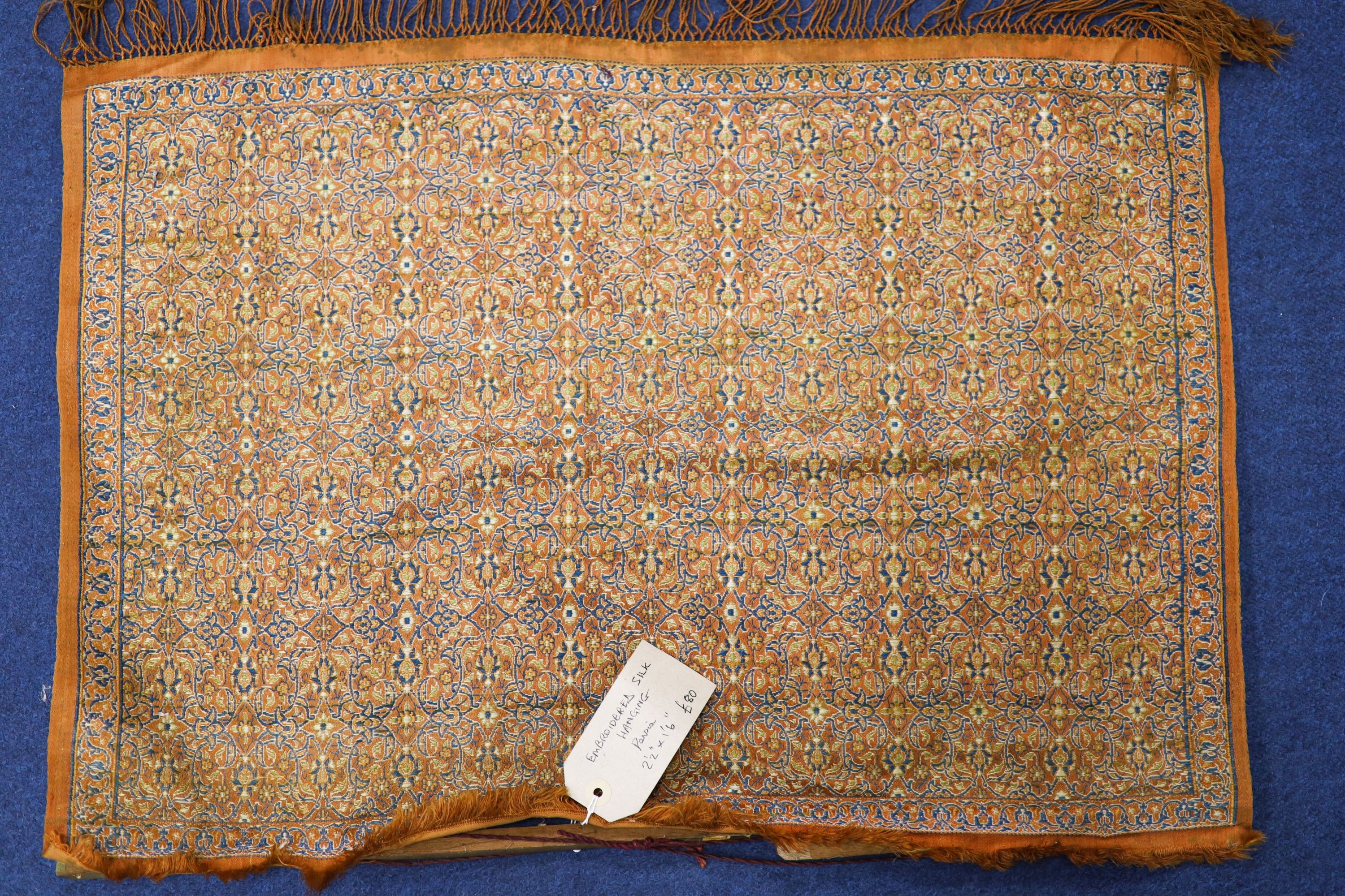 A Turkish / Persian embroidered silk panel with central armorial, 53 x 38cm. an embroidered silk hanging, 45 x 65cm and two cushions, 40 x 27cm.